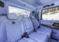 Rear seats of a Mercedes-AMG G63 XLP 800 ADVENTURE showcase quilted light blue leather upholstery, with snow-covered mountains and trees visible through the windows.