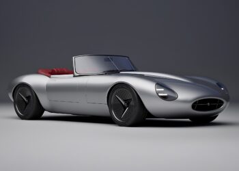 A silver convertible sports car with a sleek, aerodynamic design and red interior, shown in a studio setting—reminiscent of how former Jaguar designer Ian Callum reimagines a modern-day E-Type.