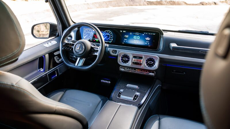 Interior view of an electrified Mercedes-Benz featuring a digital dashboard, leather seats, multifunction steering wheel, and central infotainment screen with the signature Mercedes Icon.