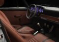 Brown leather seats and door panel, black dashboard with five illuminated gauges, a three-spoke steering wheel, manual gear shift, and aluminum pedals evoke the style of exotic cars showcased at the Celebration Exotic Car Festival.