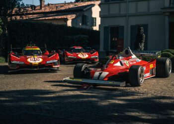 Three red Ferrari race cars, including Best of Show Winners from the Cavallino Classic Modena 2025, are parked on a stone driveway in front of a house in daylight.