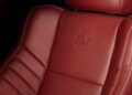 Close-up of a red leather car seat with white stitching in a 2023 Dodge Challenger SRT Demon 170, featuring an embossed devil logo on the backrest and an airbag tag—true crown jewel details for any MOPAR collector.