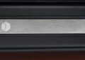 Close-up of a metallic rectangular badge with a white geometric logo, set in a black textured frame—celebrating Land Rover marks 35 years of Discovery with Gemini and Tempest Special Editions.