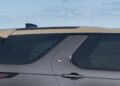 Close-up of the rear side and window of a grey Land Rover SUV with a beige roof, parked outdoors under a blue sky, celebrating Land Rover Marks 35 Years Of Discovery With Gemini And Tempest Special Editions.