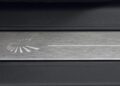 Close-up of a brushed metal surface with a white, semicircular graphic and straight line on black—an image echoing the sleek design seen in Land Rover Marks 35 Years Of Discovery With Gemini And Tempest Special Editions.
