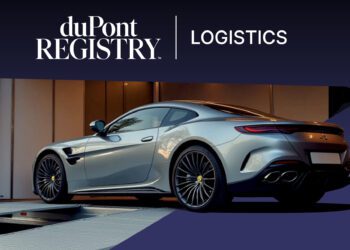A silver luxury sports car is being loaded onto an enclosed vehicle transporter with a duPont REGISTRY Logistics banner above, exemplifying premium Luxury Vehicle Transport.
