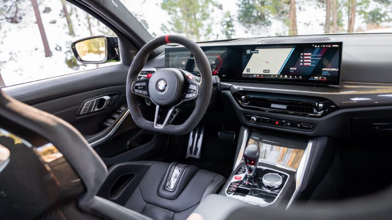 Interior view of a modern BMW car featuring a digital dashboard, multifunction steering wheel, and a central touchscreen display with controls on the center console.
