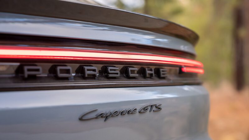 Close-up of the rear of a grey Porsche Cayenne GTS, showing the model badge, Porsche lettering, and LED tail light.