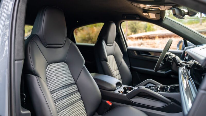 Front seats and dashboard of a modern car interior with black leather upholstery and patterned seat inserts, taken from the passenger side.