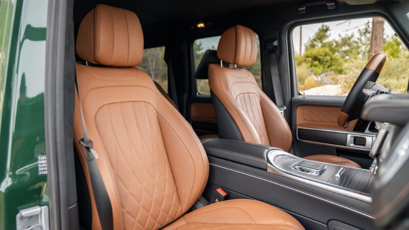 Front interior view of a vehicle showing tan leather seats with quilted stitching, a central console, and part of the dashboard.