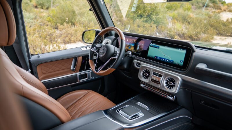 The interior of a modern Mercedes-Benz SUV with brown leather seats, a digital display dashboard, and a navigation system visible on the screen.