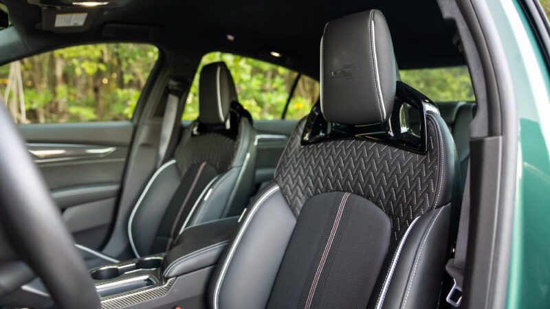 Close-up of the front seats inside a modern car, showing black leather upholstery with patterned stitching and a logo on the headrest.
