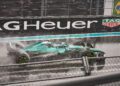A green Aston Martin Formula 1 car speeds through a wet racetrack in heavy rain, water spraying behind, as it passes a TAG Heuer ad—capturing the excitement of a Luxury Grand Prix.