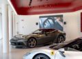 Two Ferrari sports cars, one silver and one gray, are displayed in a modern showroom with a red ceiling and track lighting, perfectly reflecting the dealer corporate identity.