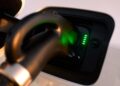 A close-up of an electric vehicle charging port with a charger plugged in and green indicator lights showing the charging status—reminiscent of the innovation seen in the Four-Door Dodge Charger Daytona muscle car sedan.