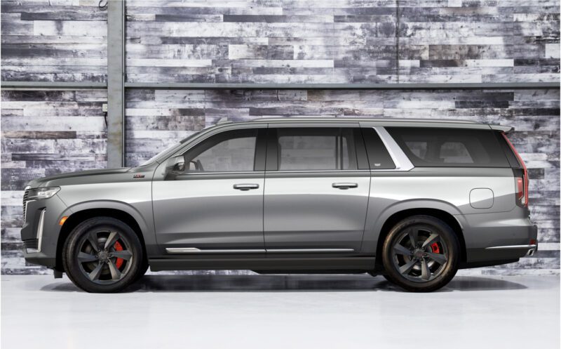 A silver SXR Series SUV with tinted windows, black wheels, and red brake calipers is parked indoors against a weathered wooden wall backdrop.