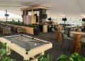 A modern lounge area with a pool table in the foreground, bar seating, high tables, and a bar counter under a large canopy.