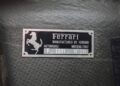 Metallic identification plate on a textured surface reads "Ferrari, Manufactured by Ferrari, Automobili Modena Italy, F-2001, N° 211," with a prancing horse logo—the same model celebrated at the Historic Monaco Sale: Ferrari F2001 at €15.98 million.