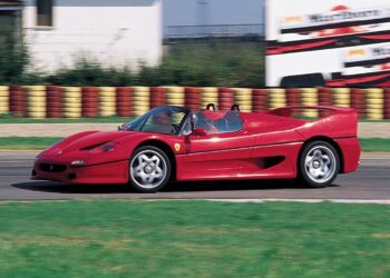A red Ferrari F50 convertible speeds along the racetrack, blurred background elements capturing the thrill of its 30th Anniversary Legacy Tour.