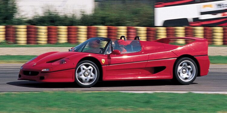 A red Ferrari F50 convertible speeds along the racetrack, blurred background elements capturing the thrill of its 30th Anniversary Legacy Tour.