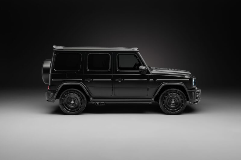 Side view of a black Mercedes-Benz G-Wagon fitted with widetrack aero kits, photographed in a studio with a dark background and soft lighting.
