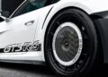 Close-up view of the rear wheel and side panel of a white Porsche GT3 RS, featuring black “GT3 RS” lettering and distinctive aerodynamic wheel covers.