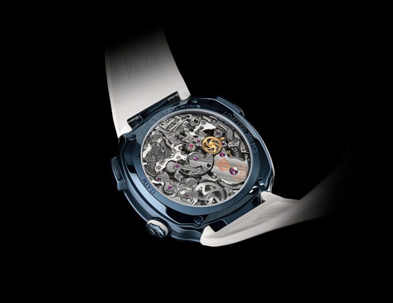 Close-up of the back of a luxury H. Moser & Cie wristwatch with a visible mechanical movement, featuring intricate gears, a transparent case, and a white strap against a black background.