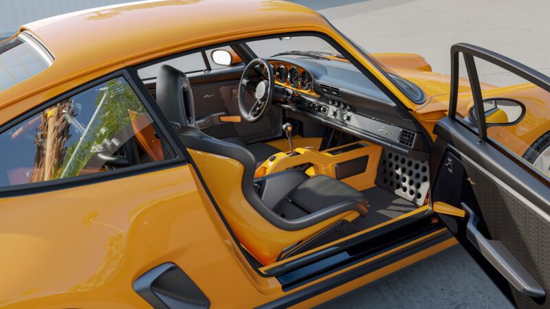 Yellow limited edition coupe with the driver's side door open, revealing a black and yellow interior, racing seats, and manual transmission. This Reimagined Porsche 911 by Singer is parked on a concrete surface.