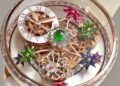 Close-up of an ornate Jacob & Co. watch face with Roman numerals, exposed gears, colorful jeweled flowers, and a central green gemstone—reflecting the brand’s flair seen in its $1.3B beachfront development south of Dubai.