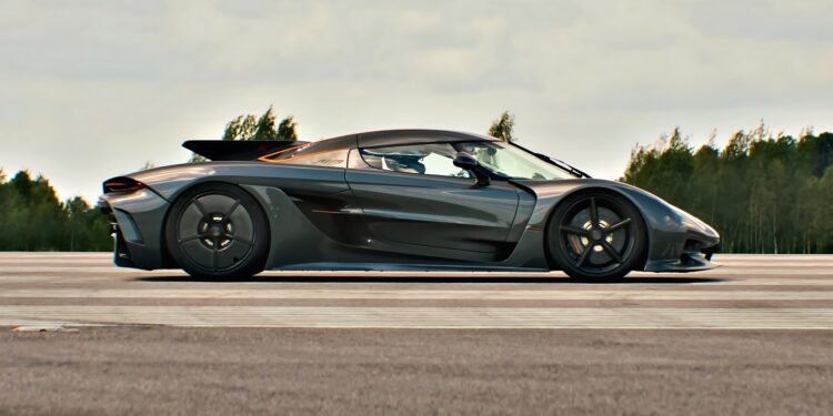 A sleek black sports car, reminiscent of the Koenigsegg Jesko Absolut, is parked on a road lined with trees under a cloudy sky, exuding power worthy of the 1/2 Mile Top Speed Record.