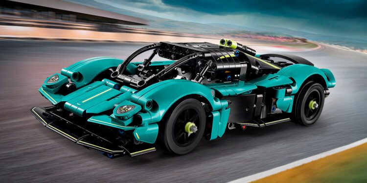 A teal and black LEGO Technic toy race car model with detailed mechanical features, inspired by the Aston Martin Valkyrie, drives on a blurred racetrack under a cloudy sky—perfect for fans looking to buy an exciting collectible.