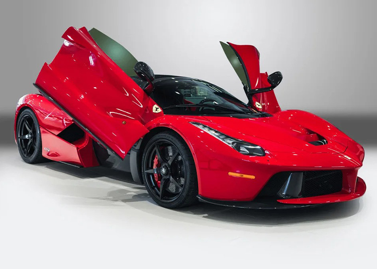 A red Ferrari LaFerrari hypercar with its butterfly doors open, shown at an angle on a neutral background.
