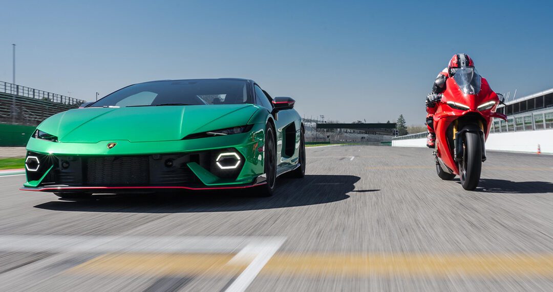 A green Lamborghini Temerario and a red Ducati Panigale V4 drive head-to-head on a racetrack under a clear blue sky.