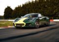 A green Lotus Emira Jim Clark Edition with a yellow stripe speeds around a racetrack curve, with trees in the background.