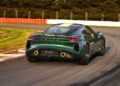 A green Lotus Emira Jim Clark Edition sports car drives on a racetrack, viewed from the rear.