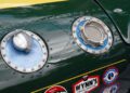 Close-up of a green vintage Lotus race car’s fuel cap and oil filler, with various racing stickers—including “Wynn’s” and “Indianapolis 500”—visible below. This rare 1-of-60 Emira Jim Clark Edition pays tribute to racing legends.