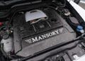 Close-up view of a car engine with a large black Mansory-branded engine cover, various components, and fluid reservoirs visible around the Speranza G-Class Convertible’s engine bay.