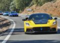 A yellow Maserati sports car leads a group of luxury cars on a winding mountain road under clear skies, as Maserati takes the spotlight at 2025 FuoriConcorso with the GT2 Stradale and MCXtrema.