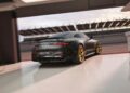 A black, limited-run Mercedes-AMG coupe with gold wheels is parked in a garage near a racetrack at sunset, evoking the high-octane thrill of a Brad Pitt F1 film.