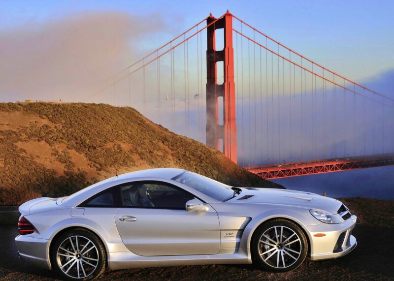 A silver sports car—the only Mercedes-AMG Black Series to feature a V12—parked in front of the Golden Gate Bridge, with hills and fog in the background.
