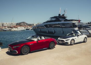 Two modern convertibles, including a striking Mercedes-Maybach SL 680, are parked on a marina dock before a luxury yacht, with other boats and waterfront buildings in the background. The 2026 Mercedes-Maybach will soon be available at select US dealers.