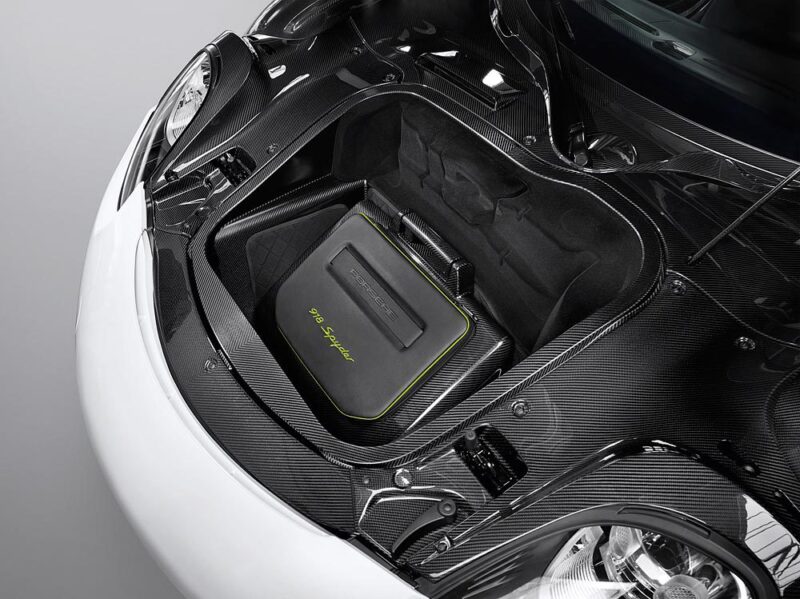 An open car front trunk reveals a black Porsche-branded bag with green accents labeled "918 Spyder" inside a carbon fiber compartment, highlighting details perfect for any Comparison: Porsche Carrera GT Vs Porsche 918 Spyder enthusiast.