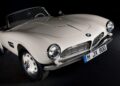 A classic white BMW convertible sports car with round headlights and a front license plate reading "M JX 800" against a dark background—showcasing how this BMW went from bold gamble to blue-chip classic.