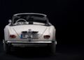A rear view of a classic white BMW convertible with a vintage license plate, displayed against a black background—showing how this BMW went from bold gamble to blue-chip classic.