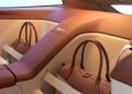 A brown leather handbag is secured in a designated compartment within the tan and brown leather interior of a Shooting Brake luxury car.