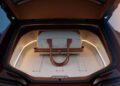 A duffel bag is placed inside the open front trunk of a BMW with beige interior and ambient lighting, highlighting the versatility of this Shooting Brake.