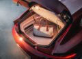 A beige and brown duffel bag is placed in the open trunk of a red BMW Shooting Brake.