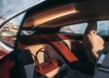 View of a BMW Shooting Brake’s rear interior with cream leather seats, a brown leather handbag on the seat, and a scenic mountain landscape visible through the window.