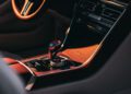 Close-up of a Shooting Brake’s center console featuring a gear selector, control knobs, and dashboard, with sunlight highlighting the refined interior.