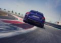 A blue BMW 2026 M2 CS, boasting 523HP, speeds around a curve on the racetrack under the sunny sky, viewed from behind.